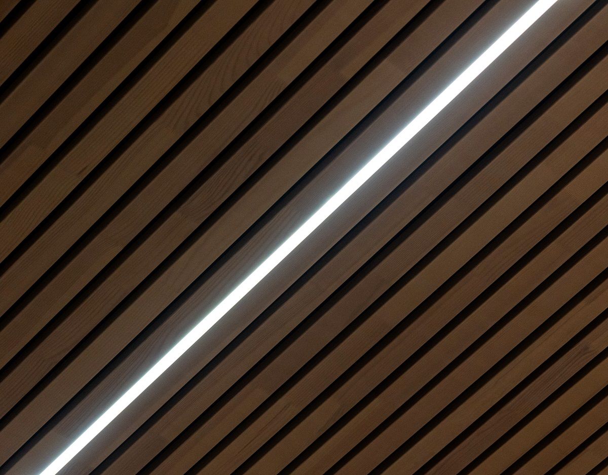 Primo piano di una soluzione per controsoffitti, profilo in alluminio e striscia LED regolabile in temperatura di colore nella scanalatura della lastra del soffitto